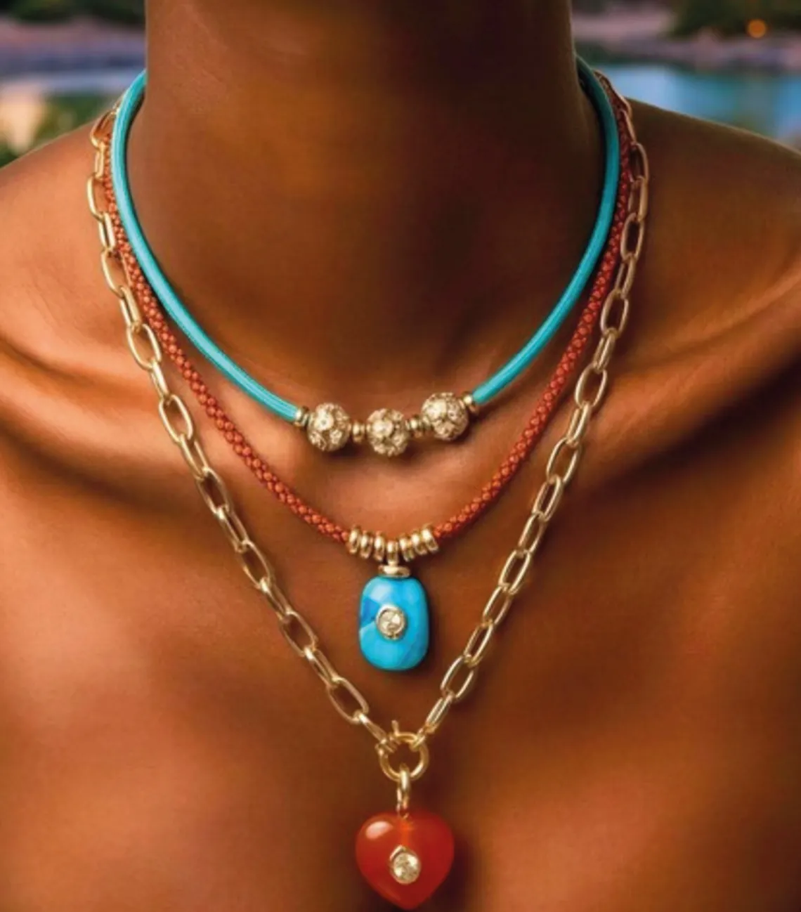 Modelo usando três colares da coleção Oásis Urbano: cordão turquesa com esferas, cordão terracota com pedra azul e corrente com coração de jaspe laranja